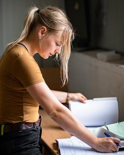 Photo by Adobe Stock. A young woman looks over budgeting paperwork.